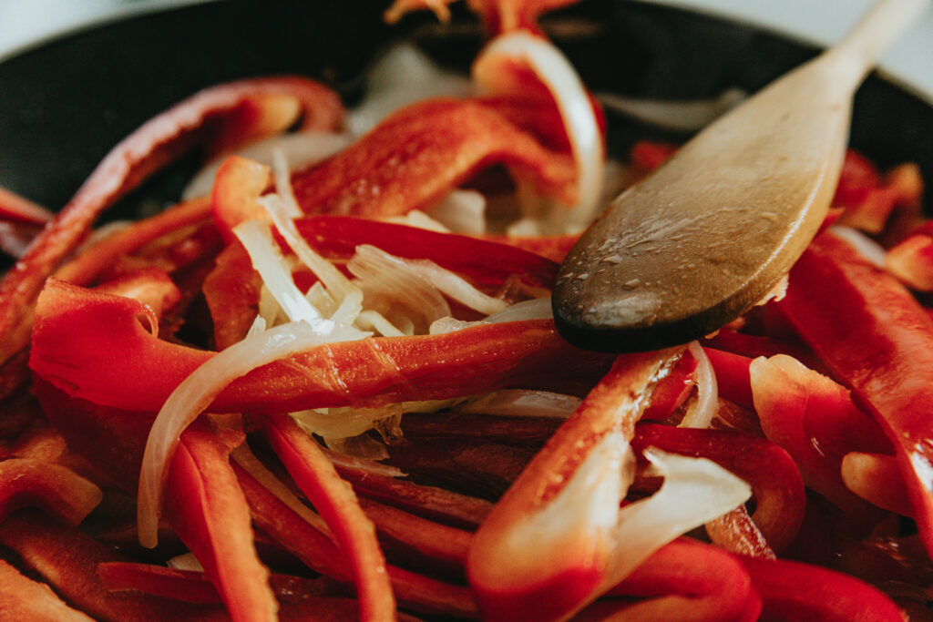 close-up-of-white-onions-and-red-peppers-cooking-in-a-pan