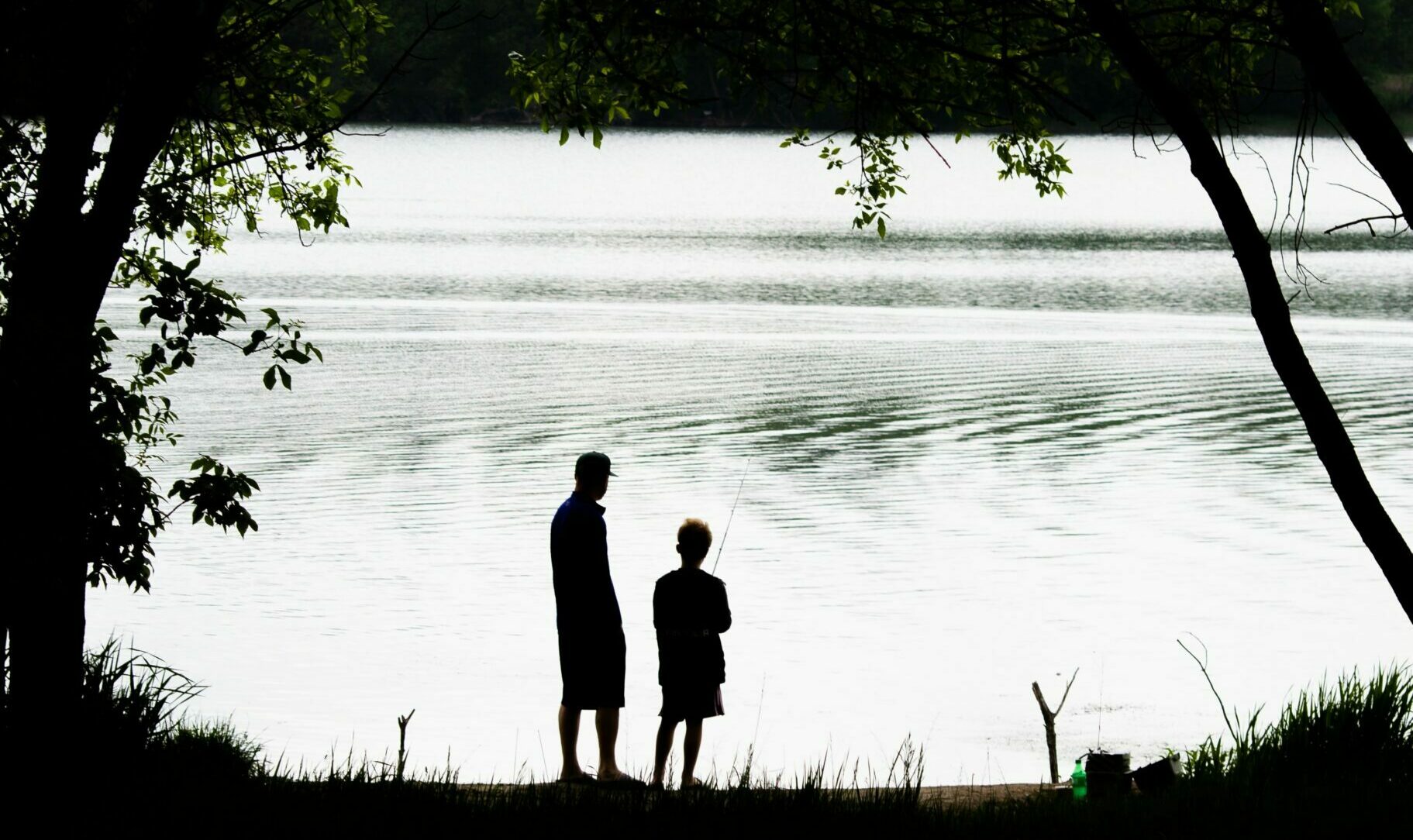 father and son fishing next to lake
