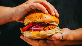 working in a restaurant job, two hands serving a burger