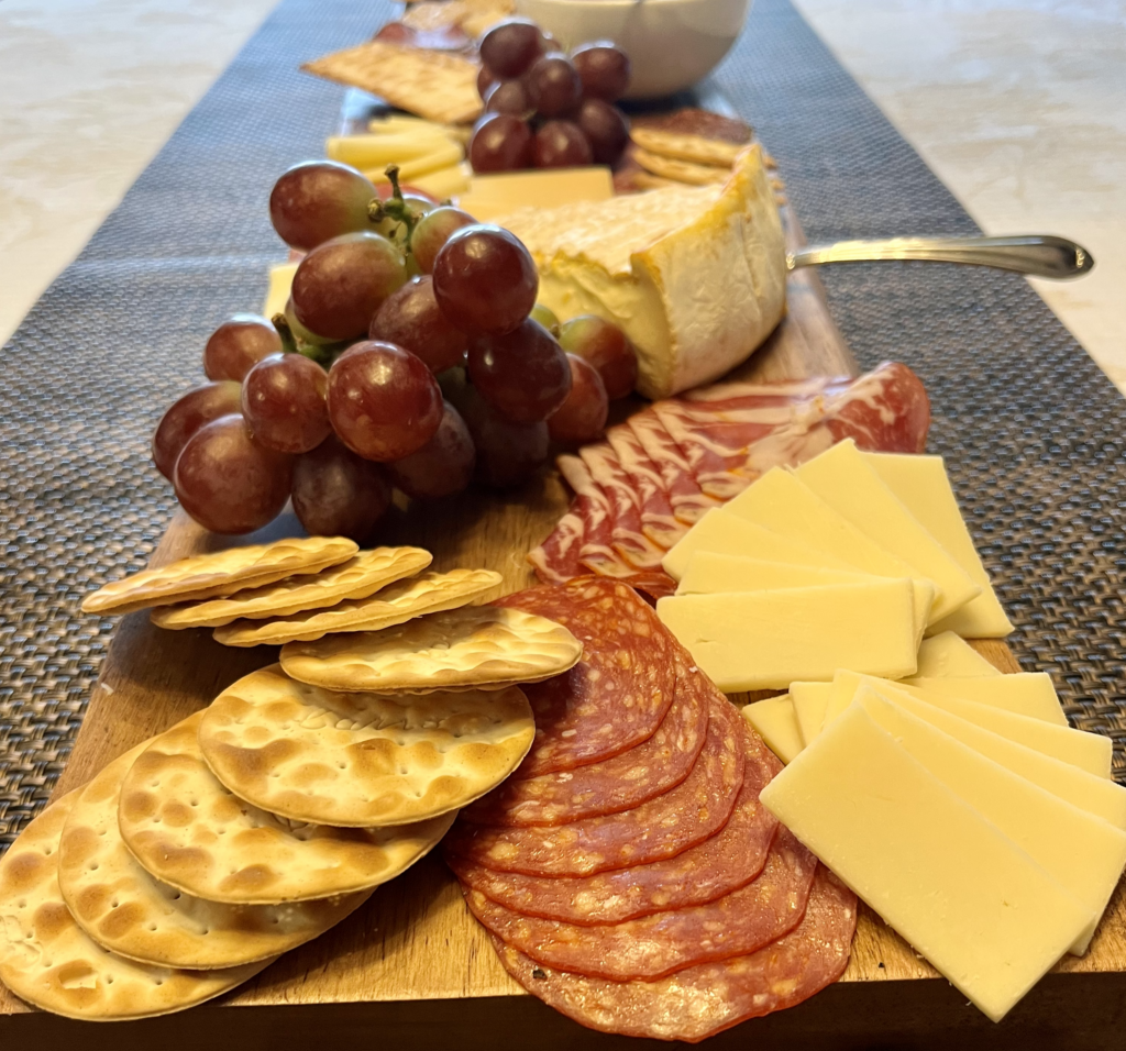 charcuterie board with grapes, crackers, cheese, and meat
